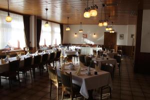 a dining room with tables and chairs with white tablecloths at Hotel Ceteno in Wunstorf