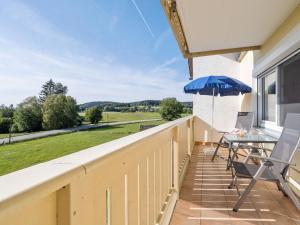 a balcony with a table and an umbrella at Spacious apartment in the Bavarian Forest in Viechtach