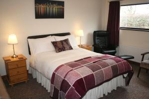 ein Schlafzimmer mit einem Bett, einem Stuhl und einem Fenster in der Unterkunft Ken-Mar House Bed and Breakfast in Ballymoney