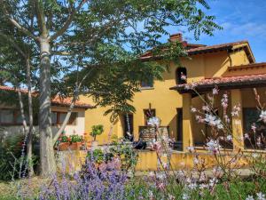 una casa amarilla con flores delante en Belvilla by OYO Podere Pulicciano Pozzo, en Pian di Scò