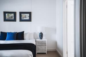 a white bedroom with a bed and a nightstand with at Barkers Run Terrace in Castlemaine