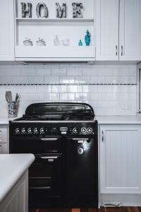 a black stove in a kitchen with white cabinets at Barkers Run Terrace in Castlemaine