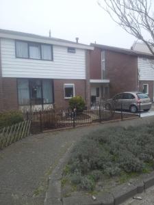 ein Haus mit einem Zaun und einem Auto vor dem Haus in der Unterkunft Studio de Aankomst in De Koog