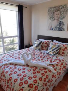 1 cama con 2 toallas en forma de corazón en Condominio Reino de Italia, Serena, en La Serena