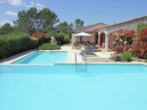 a large blue swimming pool next to a house at Gorgeous Villa in Bagnols en For t in Bagnols-en-Forêt