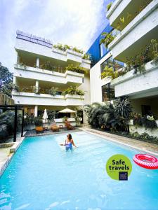a woman in a swimming pool next to a building at Che Suites Tulum in Tulum