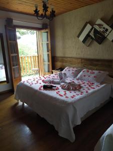 a bedroom with a bed with red flowers on it at Pousada Vila Floratta in Campos do Jordão