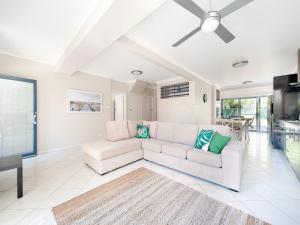 a living room with a white couch and a ceiling fan at Magnolias in Fingal Bay