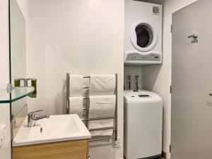 a bathroom with a sink and a washing machine at Ramada Suites by Wyndham Albany in Auckland