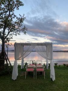 un tavolo e sedie sotto un baldacchino vicino all'acqua di The Riviera Champasak a Champasak