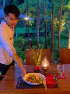a man standing at a table with a bowl of food at The Riviera Champasak in Champasak