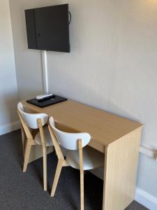 a wooden desk with two chairs and a television at Country Gardens Motel in Coonabarabran