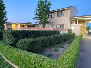 una casa con una siepe davanti di Country Gardens Motel a Coonabarabran Altre 14 foto