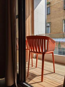 una silla roja sentada en un balcón junto a una ventana en 阡陌-頂加民宿 en Tainan