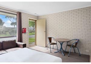 1 dormitorio con 1 cama, mesa y sillas en Discovery Parks - Warrnambool, en Warrnambool