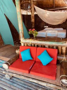 un sofá rojo con almohadas azules sentado en un porche en Emerald Gecko, en Isla Havelock