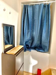 La salle de bains est pourvue d'un miroir et d'un rideau bleu. dans l'établissement Logement Agréable récemment rénové à Aubusson centre, à Aubusson