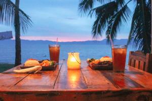 a wooden table with food and drinks on the beach at Rio Beach Resort in Alegria