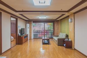 a living room with a couch and a tv at Osaek Greenyard Hotel in Yangyang