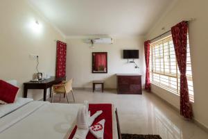 a bedroom with a bed and a desk and a table at KSTDC Hotel Mayura Shantala Halebeedu in Halebīd