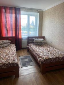 1 Schlafzimmer mit 2 Betten und einem Fenster mit Vorhängen in der Unterkunft Hotel Yuvileyny in Khrystynivka