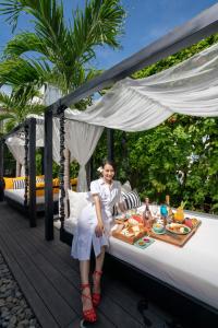 Eine Frau, die auf einem Bett mit einem Tablett Essen sitzt. in der Unterkunft Hoian Sincerity Hotel & Spa in Hoi An