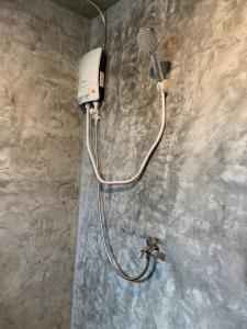 a shower with a shower head on a wall at Somphoch Garden in Trat