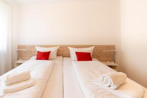 um quarto com 2 camas com almofadas vermelhas e toalhas em Bergsonne em Bad Hindelang
