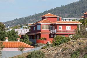 ein großes rotes Haus auf einem Hügel in der Unterkunft Casa Quintana - Apartamento Carla in Tijarafe