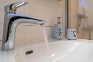 a bathroom sink with a toothbrush and two cups on it at Chalet Ramona in Grächen