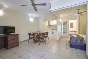 a kitchen with a dining room table and a television at Cairns Queenslander Hotel & Apartments in Cairns