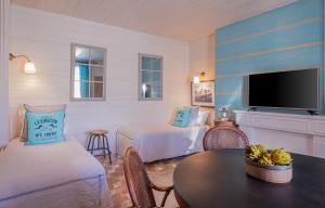 a room with two beds and a table and a tv at Appartements & Spa de la Marine Loire in Montsoreau