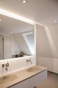 ein weißes Badezimmer mit einem Waschbecken und einem Spiegel in der Unterkunft Strön Hüs    in Hörnum