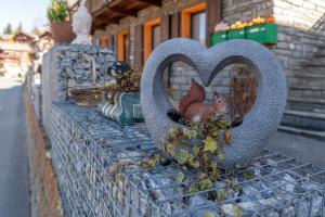 a heart shaped statue of a squirrel sitting on a fence at Chalet Ramona in Grächen