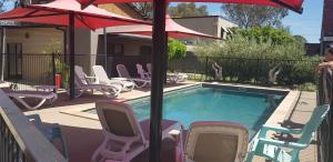 una piscina con sillas de césped y sombrilla en Adelphi Apartment 6 Riverview 2 BDRM or 6A King Studio Riverview both with balconies, en Echuca