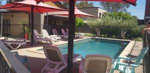 a swimming pool with lawn chairs and an umbrella at Adelphi Apartment 6 Riverview 2 BDRM or 6A King Studio Riverview both with balconies in Echuca