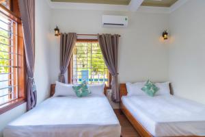 two beds in a room with a window at Cong Man Homestay Cham Island in Hoi An