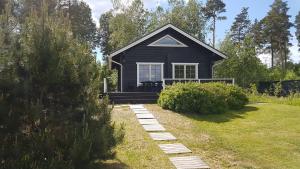 a small black house with a pathway in front of it at Kauppilan Rantasauna in Ikaalinen