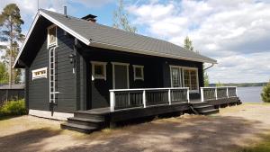a small black house with a porch and a balcony at Kauppilan Rantasauna in Ikaalinen