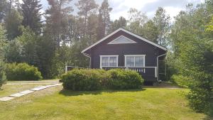 a small black house with a grass yard at Kauppilan Rantasauna in Ikaalinen
