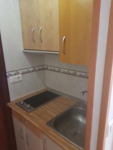 a small kitchen with a sink and wooden cabinets at Acogedor estudio en el centro torremolinos in Torremolinos