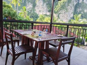 y balcón con mesa y sillas de madera. en The Cliff Elegance Resort, en Ao Nang Beach