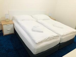 1 cama grande con sábanas blancas y almohadas. en Penzión Pohoda en Nové Zámky