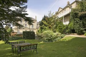 two benches sitting in the grass in front of a house at Lansdown Grove Hotel in Bath