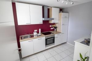 a kitchen with white cabinets and a red wall at Ferienwohnung Eifelurlaub in Daun