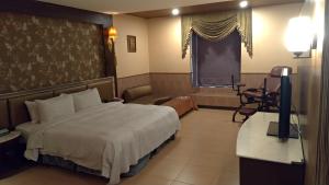 um quarto com uma cama, uma televisão e uma mesa em I Travel Motel em Kaohsiung