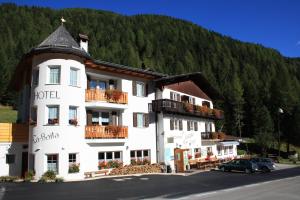 un gran hotel blanco frente a una montaña en La Baita, en Livinallongo del Col di Lana