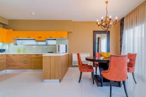 a kitchen with orange cabinets and a table and chairs at Palatia Caeli SeaFront Villas, By ThinkVilla in Makris Gialos