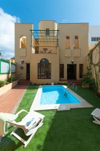 a villa with a swimming pool in front of a house at The Yellow House - Solarium - Climatized Pool in Gáldar