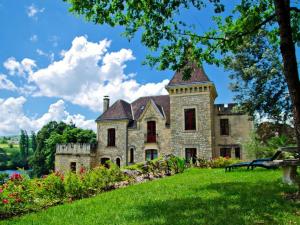 ヴェザックにあるmanoir de la malartrieの緑の芝生に塔のある古い石造りの家